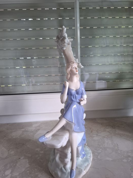 Piękna porcelanowa figurka dziewczyna siedząca na drzewie