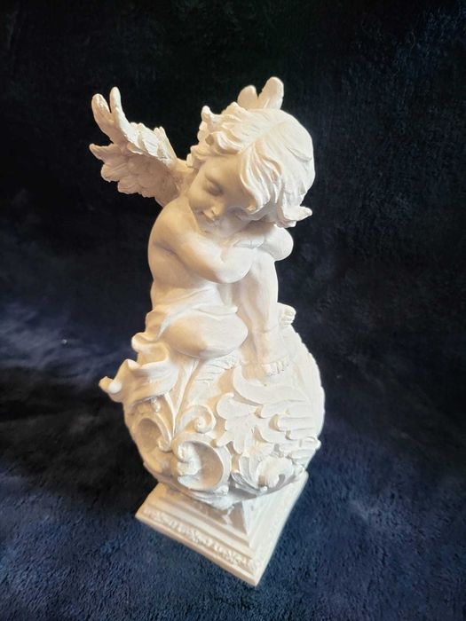 Querubim (anjo-bebé) sentado numa esfera ornamentada em Marfinite