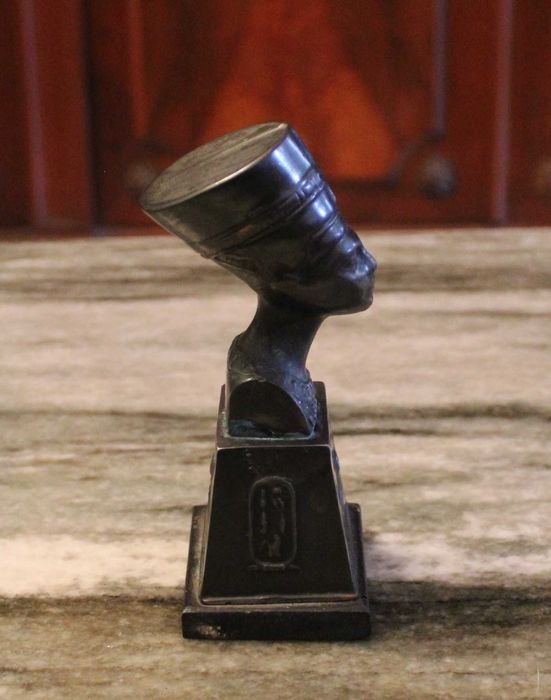 Busto de Nefertiti com 15,5cm de altura em metal sobre madeira.