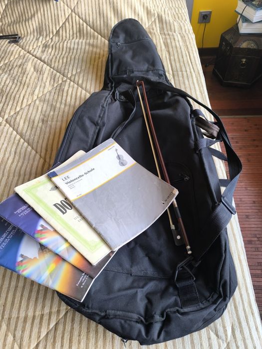 Capa para violoncelo, arco e livros diversos