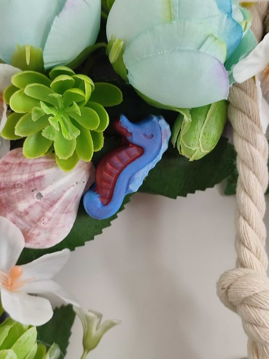 Guirlanda artesanal marítima com flores, conchas e farol decorativo