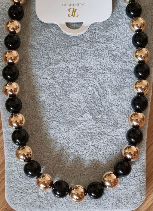 Colar dourado, em aço, às bolinhas douradas intercaladas com pretas. Leve.