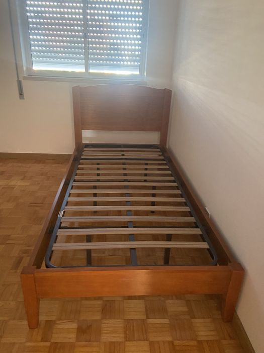 Cama individual de madeira macica e uma mesa de cabeceira