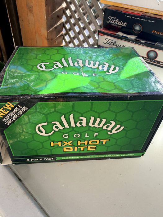 Bolas de golfe novas nas caixas e de treino