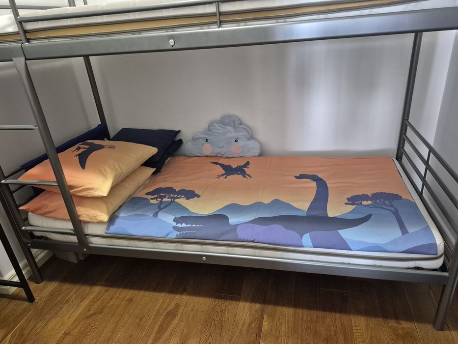 Łóżko piętrowe zmateracami i pościelą w dinozaury