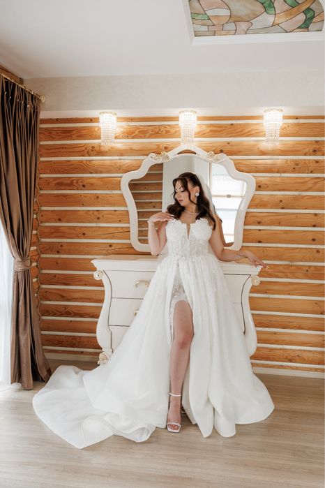 Весільна сукня білого кольору оздоблена квітами з розрізом