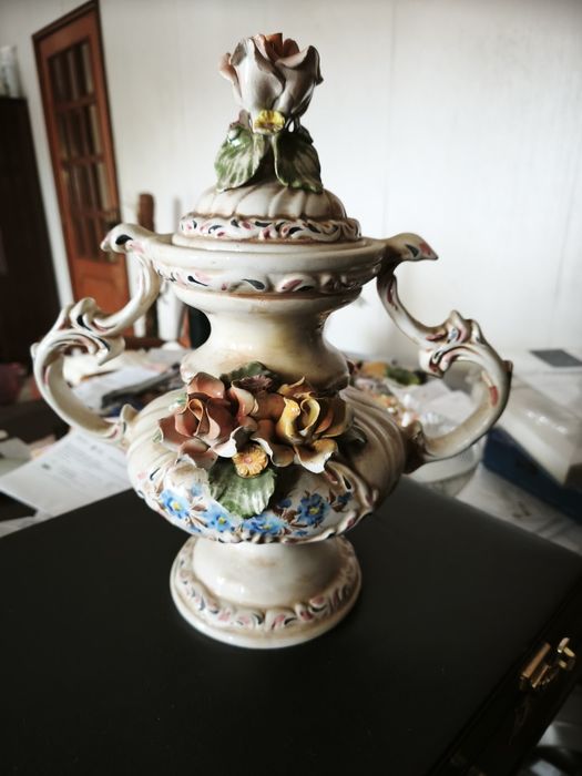 peça cerâmica decorativa ou uma peça de porcelana. Tem a forma de um vaso ou urna com duas pegas, com uma tampa separada
