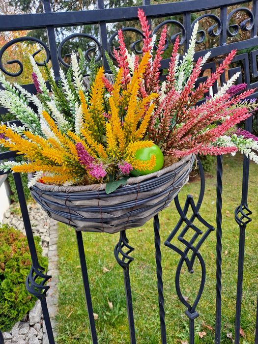 Wrzosy sztuczne w koszyku na ogrodzenie.