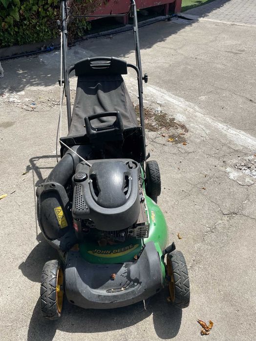 Máquina de cortar relva a gasolina, marca John Deere a funcionar em pleno
