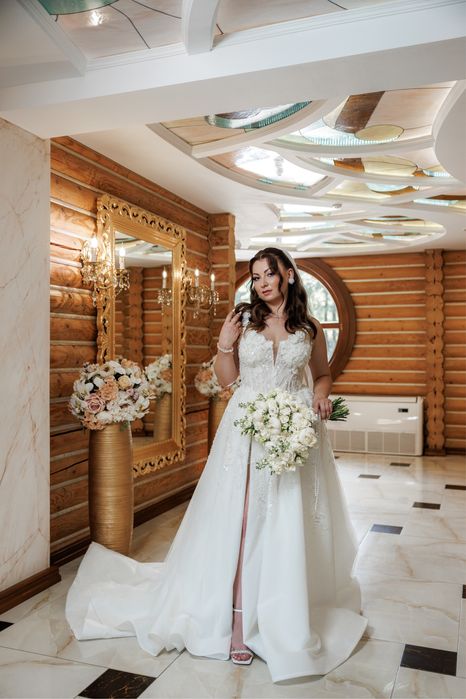 Весільна сукня білого кольору оздоблена квітами з розрізом