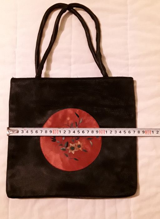 Bolsa ou mala de mão preta com aplicação circular vermelha