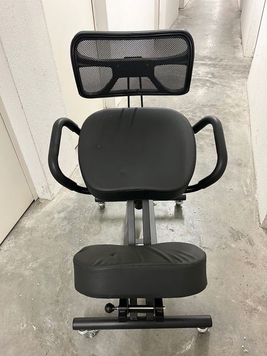 Cadeira ergonómica preta com apoio para costas e joelhos