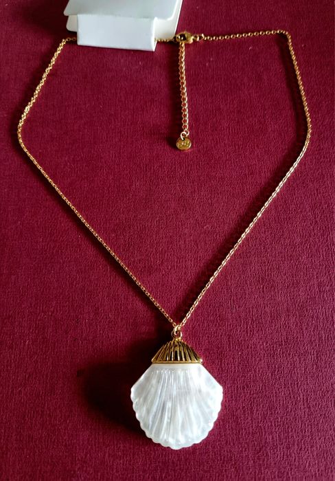 Colar dourado, em aço, com concha em madrepérola.  Tem extensor.