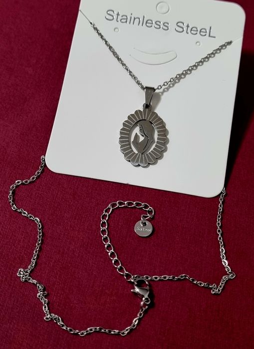 Colar prateado, em aço, com pingente da Nossa Senhora. Tem extensor