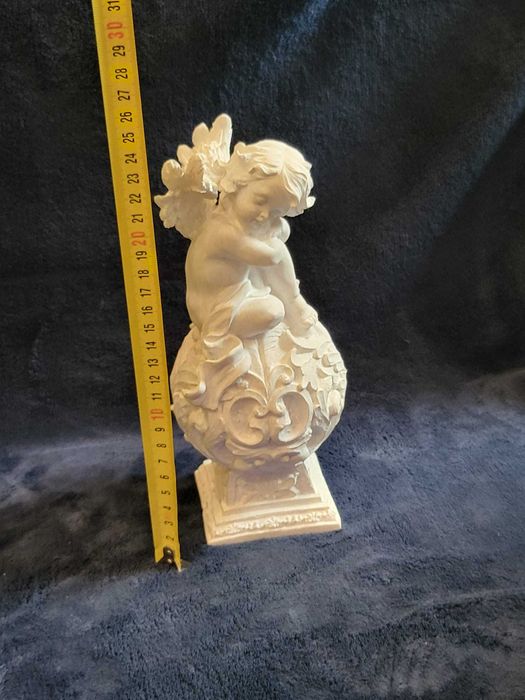 Querubim (anjo-bebé) sentado numa esfera ornamentada em Marfinite
