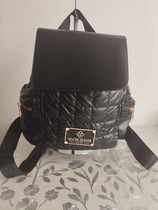 Nowy plecak wykonany z ekoskóry i materiału kurtkowego od firmy M&M Bags. Kolor czarny. Doskonały dodatek do codziennych stylizacji.Po bokach 2 kieszo