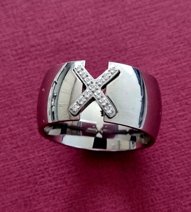 Anel grosso prateado, em aço, com um X em zirconias. T20