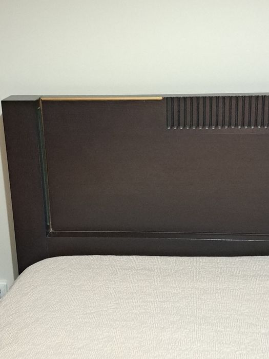 Cama de casal,  cor castanho escuro, com iluminação.