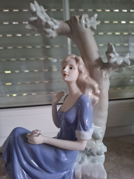 Piękna porcelanowa figurka dziewczyna siedząca na drzewie