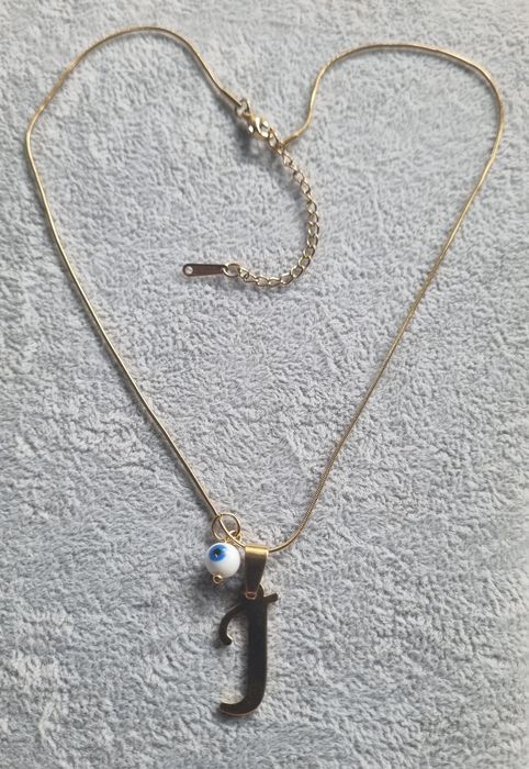 Colar dourado, em aço, com a letra "J" e olho turco. Tem extensor