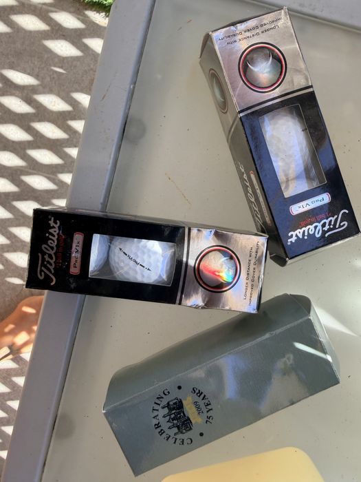 Bolas de golfe novas nas caixas e de treino