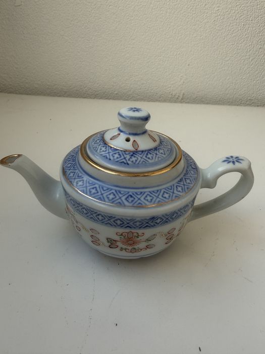 Bule em porcelana azul e branca com decoração dourada.
