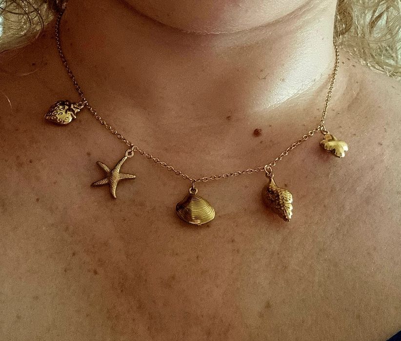 Colar dourado, em aço, com 5 pingentes diferentes. Tem extensor.
