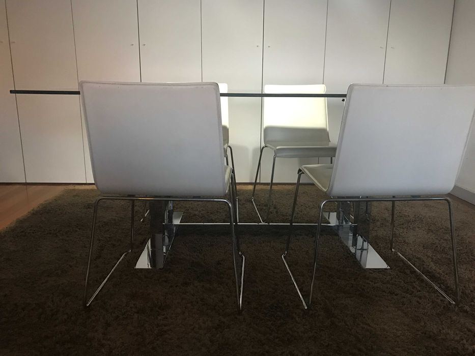 quatro cadeiras de pele branca e base em inox