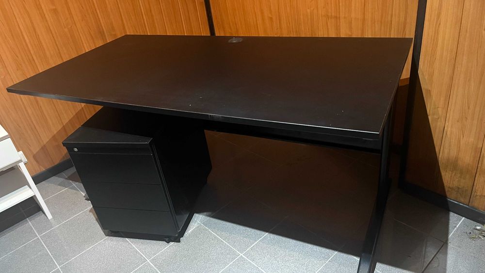 Secretária preta e modulo de gavetas.