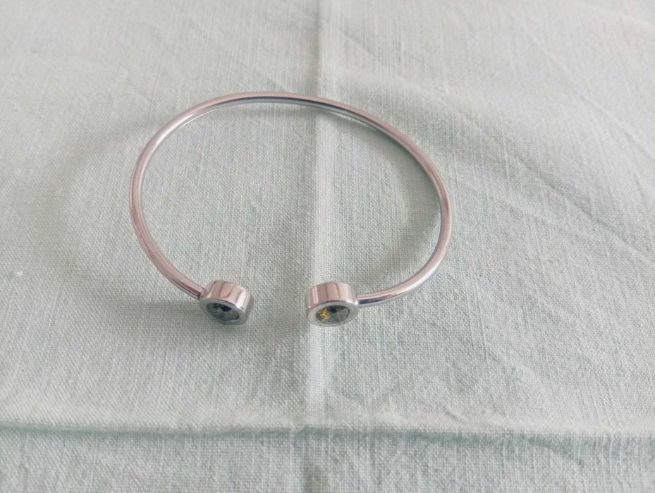 Pulseira, tipo escrava, em metal prateado e detalhes com pedra verde, nas pontas