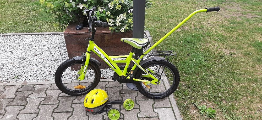 Zielony rower Alpino w komplecie z bocznymi kółkami, kijem i kaskiem.