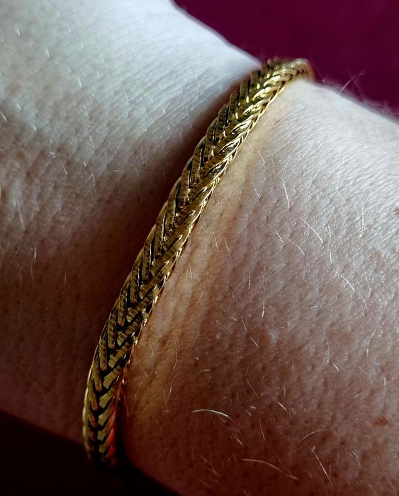 Pulseira dourada, em aço inoxidável. Tem extensor
