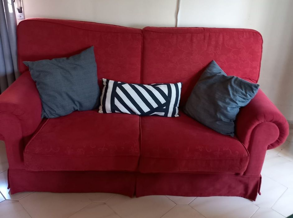 Sofá vermelho de dois lugares com cama articulada no seu interior