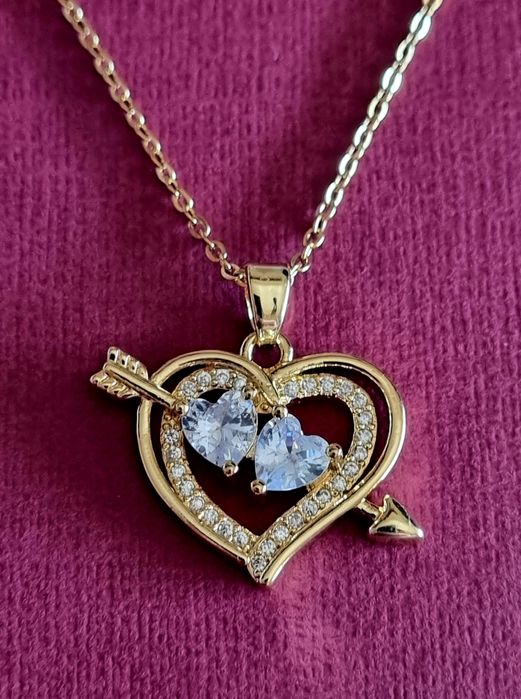 Colar dourado, em aço, com 2 corações unidos por uma flecha.