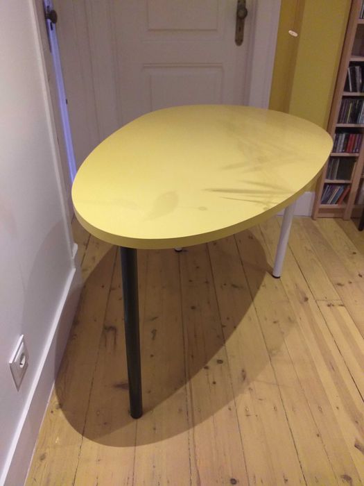 Mesa design oval com cor amarela, uso versátil.