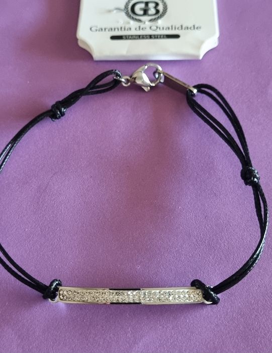 Pulseira preta e prateada, em aço. Chapinha com 2 fiadas de zirconias. Ajustável