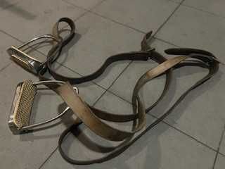 Um par de estribos metálicos com suspensões em couro