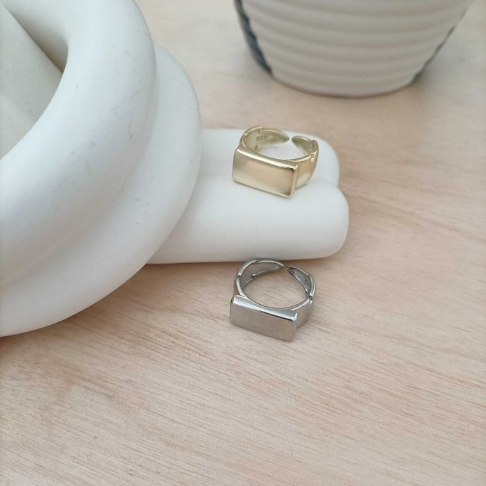 Conjunto de anéis em aço, um dourado e outro prateado.