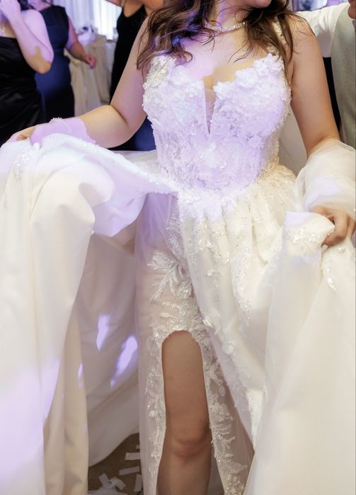 Весільна сукня білого кольору оздоблена квітами з розрізом