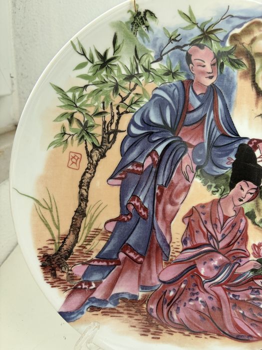 Prato decorativo em porcelana chinesa representando figuras.
