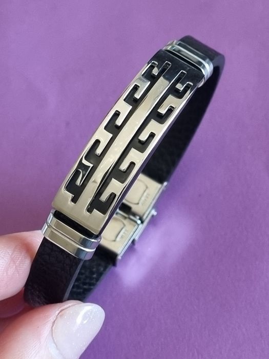 Pulseira de cabedal preto com peças prateadas em aço inoxidável.