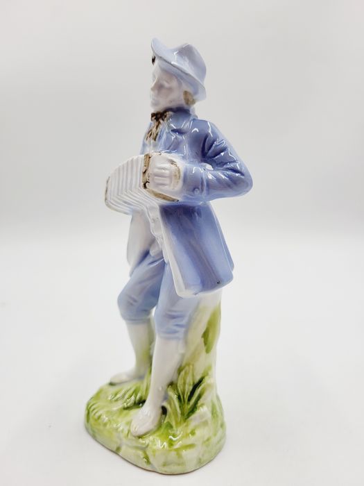 Ceramiczna pastelowa figurka muzykanta grajka z harmonią