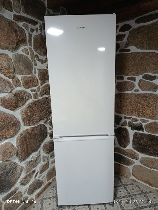 Um sofá cama, três Tvs e um refrigerador.