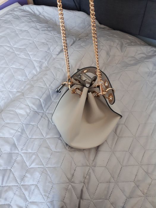 Szara torebka ze złotymi elementami.