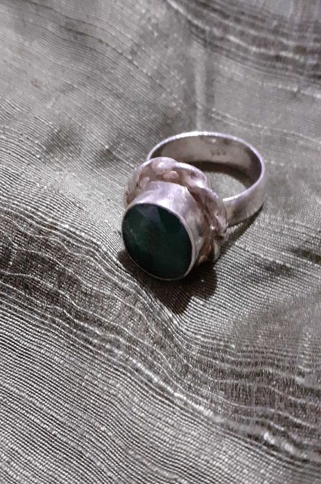 Anel em metal com pedra verde em destaque