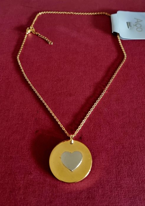 Colar dourado, em aço, com pingente redondo dourado e um coração prateado no centro