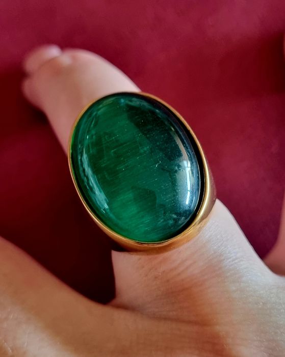 Anel dourado, em aço, com grande pedra verde oval. T17