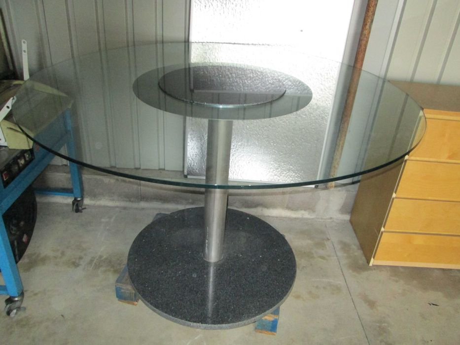 Mesa redonda com centro em granito e tampo de vidro.