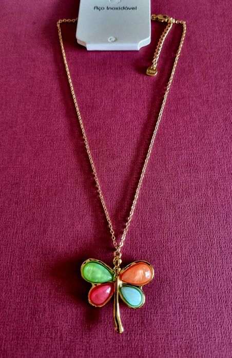 Colar dourado, em aço, com libelinha colorida. Tem extensor