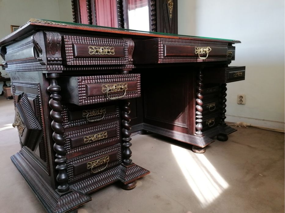 Escritório em Pau Santo, com mesa com tampo de vidro. Um cadeirão e duas cadeiras. Com móvel livros.